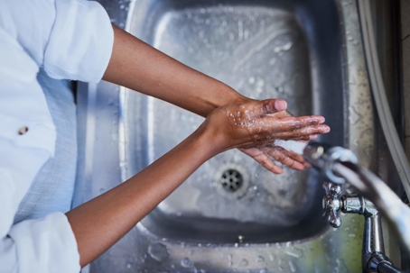 woman washing hands in stainless steel sink