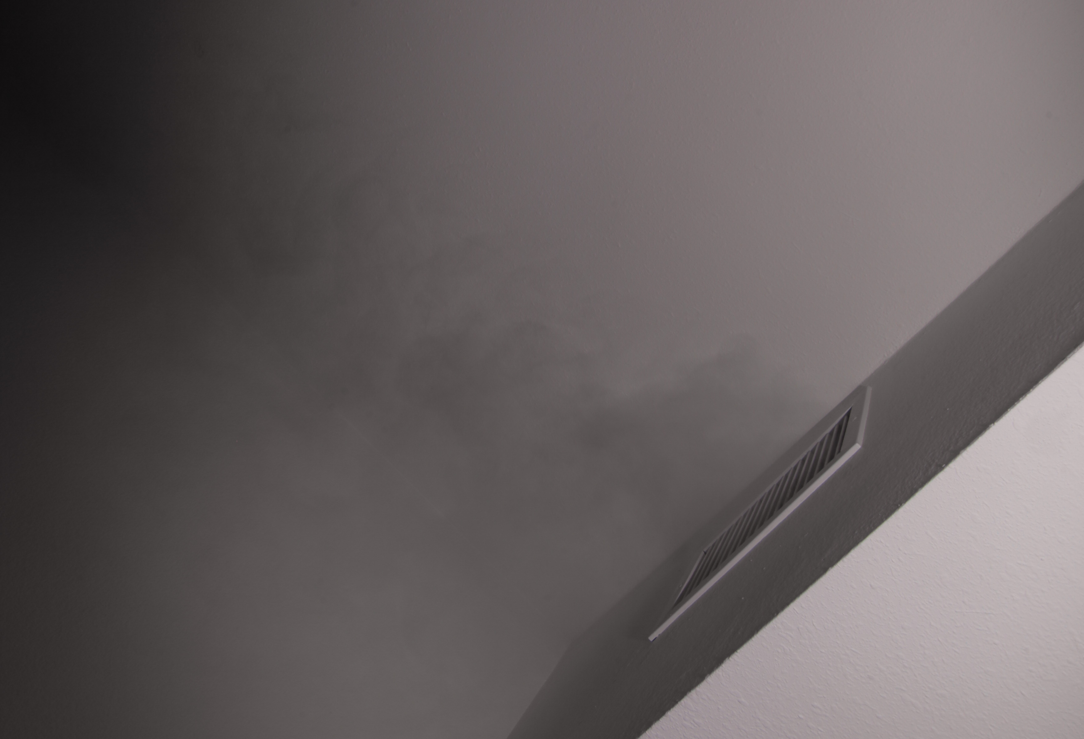 Close-up of dense FogTrace fog escaping near an air conditioning vent during a plumbing smoke test